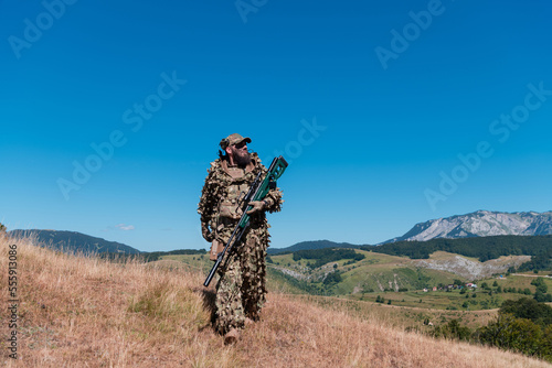 Army soldier holding a sniper rifle with scope and walking in the forest. war, army, technology and people concept.