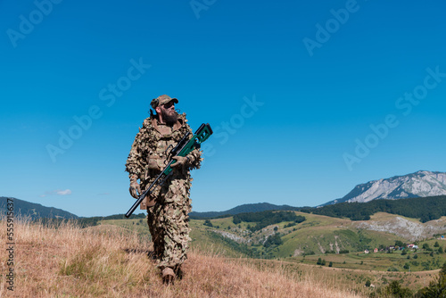 Army soldier holding a sniper rifle with scope and walking in the forest. war  army  technology and people concept.