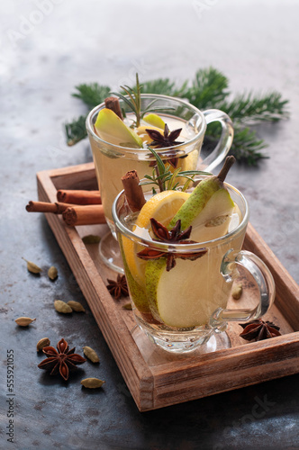 Ambiente von hellem Glühwein mit Zitronenscheiben, Birnenscheiben und Gewürzen auf hölzernem Tablett photo