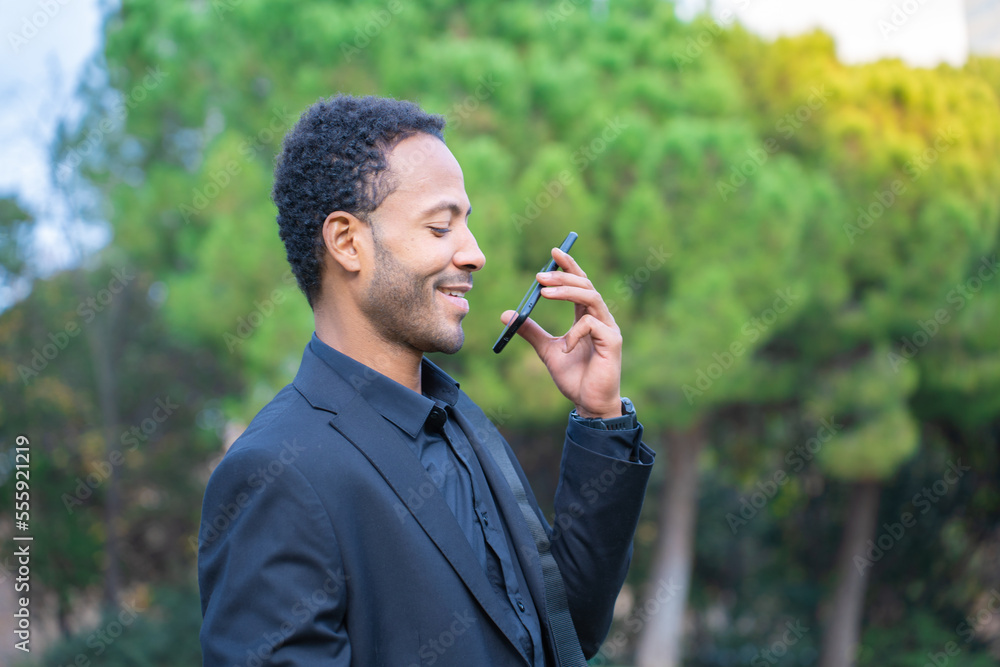 Close up portrait of attractive young black man talking on mobile phone outdoors in the city park. High quality photo Close up portrait of attractive young black man talking on mobile phone outdoors in the city park. High quality photo