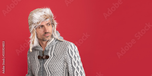 confident mature guy. man in earflap hat. grizzled guy in sweater on red background.