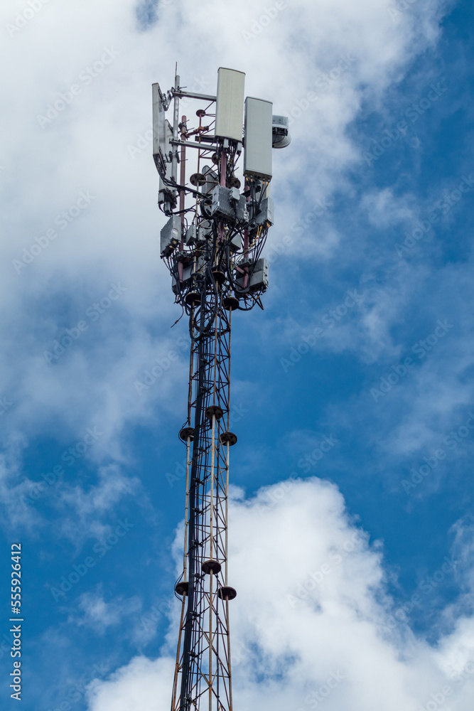 Mobile telecommunication tower with antennae and electronic communications equipments on blue sky with clouds Mobile telecommunication tower with antennae and electronic communications equipments on blue sky with clouds
