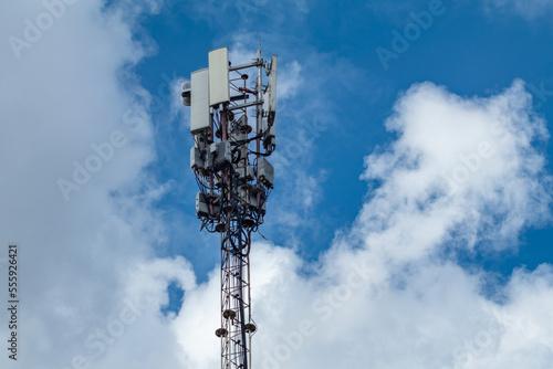 Mobile telecommunication tower in clouds, cell tower with antennas and electronic communications equipments