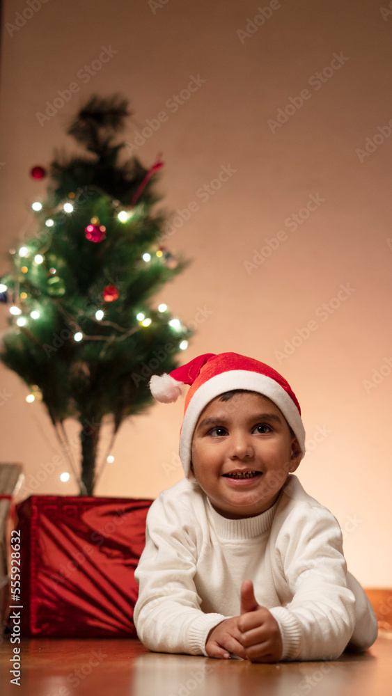child boy with christmas tree wearing santa cap child boy with christmas tree wearing santa cap