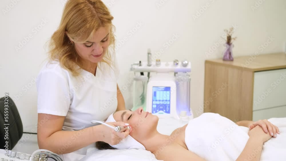 The cosmetologist performs the procedure of diamond resurfacing of the face. The specialist looks at the camera and smiles. Slow motion horizontal video The cosmetologist performs the procedure of diamond resurfacing of the face. The specialist looks at the camera and smiles. Slow motion horizontal video