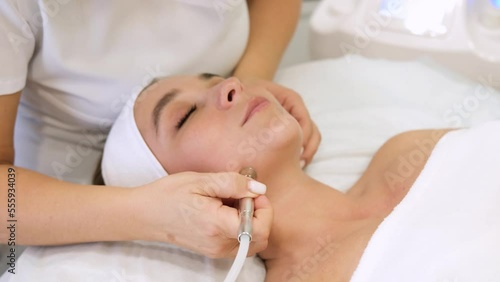 The cosmetologist makes the procedure Microdermabrasion of the skin of the face of a beautiful, young woman in a beauty salon. Cosmetology and professional skin care. Slow motion horizontal video