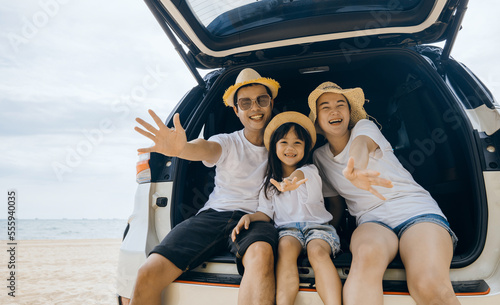 Family Day. Parents and children daughter enjoying road trip sitting on family back car motion wave to camera, Family traveling in holiday at beach, Happy people having fun in summer vacation on beach
