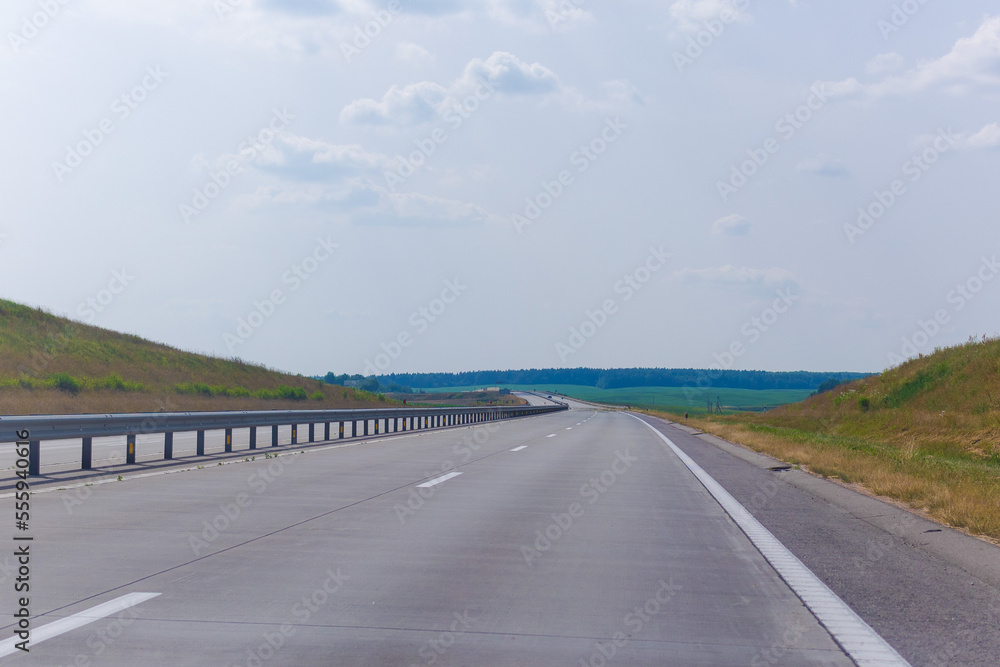 Fototapeta premium Highway wide road, transport and blue sky with clouds on a summer day