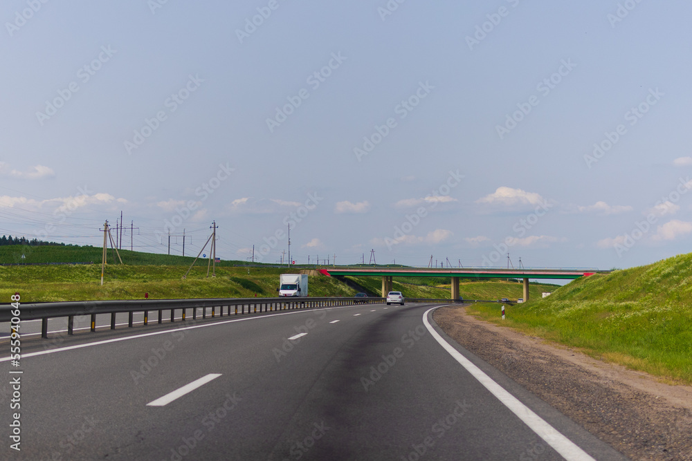 Fototapeta premium Highway wide road, transport and blue sky with clouds on a summer day