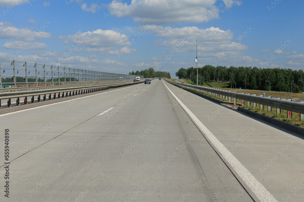 Highway wide road in the city, transport and blue sky with clouds on a summer day