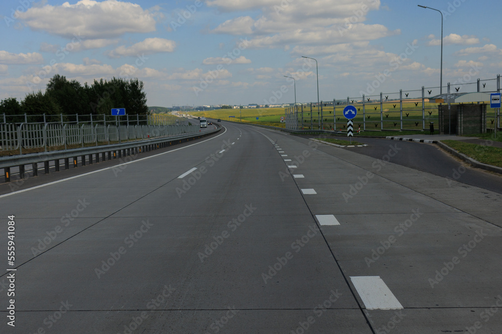 Fototapeta premium Highway wide road in the city, transport and blue sky with clouds on a summer day