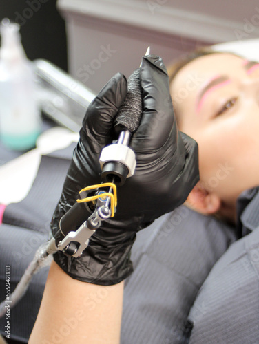 Cosmetologist applying permanent make up eyebrows for a client in a salon.Microblading