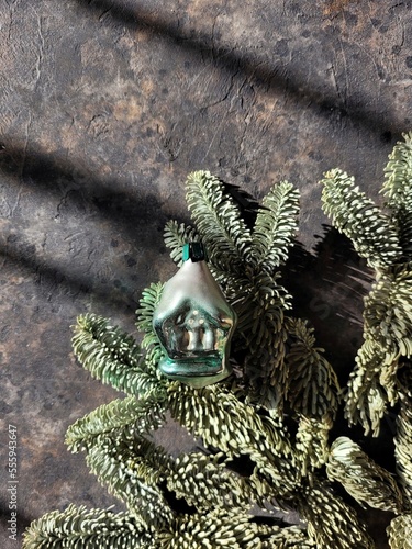 Fir branches with christmas ball in the shape of russian rustic home. Top view on glass retro christmas ball and nobilis branch on the black table. New year concept.  photo