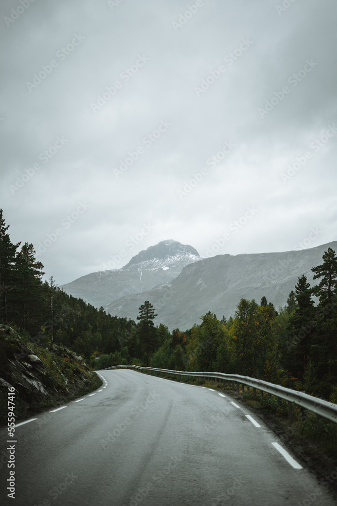An empty road leading to the mountains on a rainy autumn day in Norway