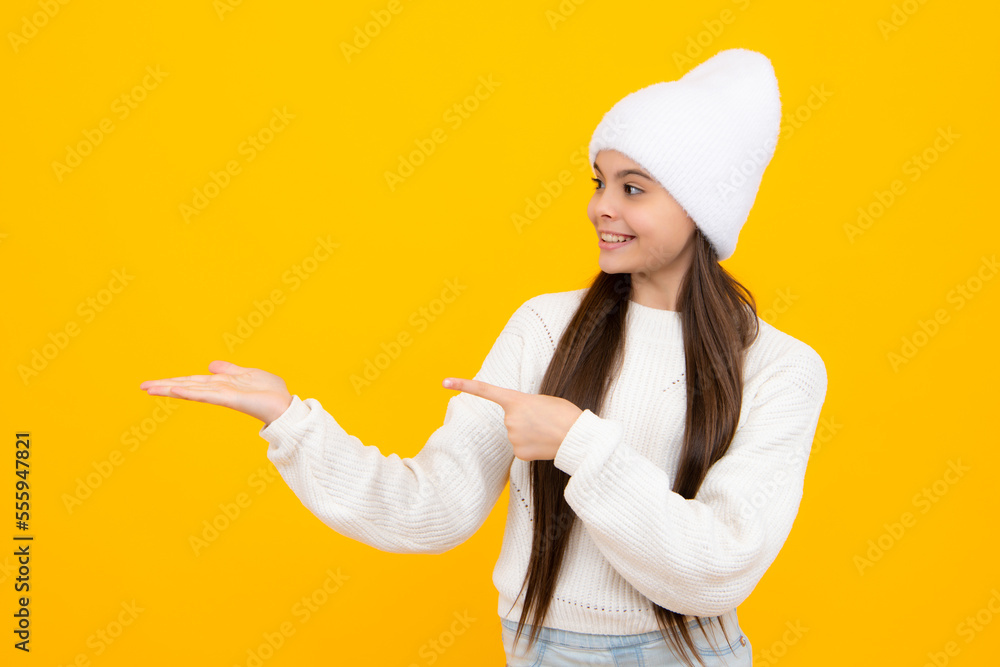 Portrait of cute teenager child girl pointing hand showing adverts with copy space over yellow background. Portrait of cute teenager child girl pointing hand showing adverts with copy space over yellow background.
