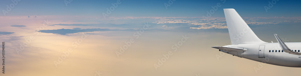 Obraz premium Passenger airplane at cloudy sky background in pastel colors with copy space. Wide landscape over the sea with an aircraft in sunrise beams for your travel concept of air trip or transportation.