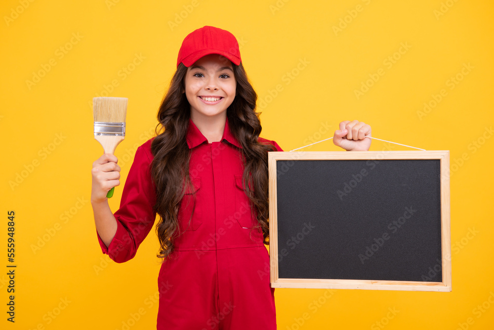 Happy smiling teenager girl builder in building uniform and cap. Painter with painting brush tool or paint roller. Worker isolated on yellow background. Kids renovation concept. Happy smiling teenager girl builder in building uniform and cap. Painter with painting brush tool or paint roller. Worker isolated on yellow background. Kids renovation concept.