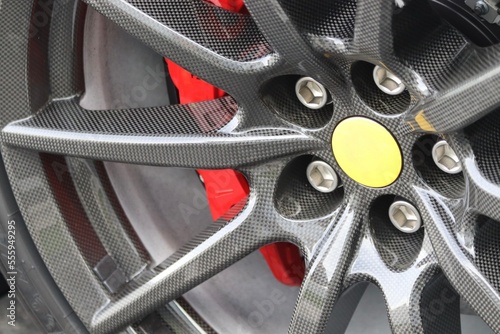 Closeup of a sports car wheel/ Precision engineering on display/ Red brake caliper adds a touch of aggression/ A symbol of performance and power.