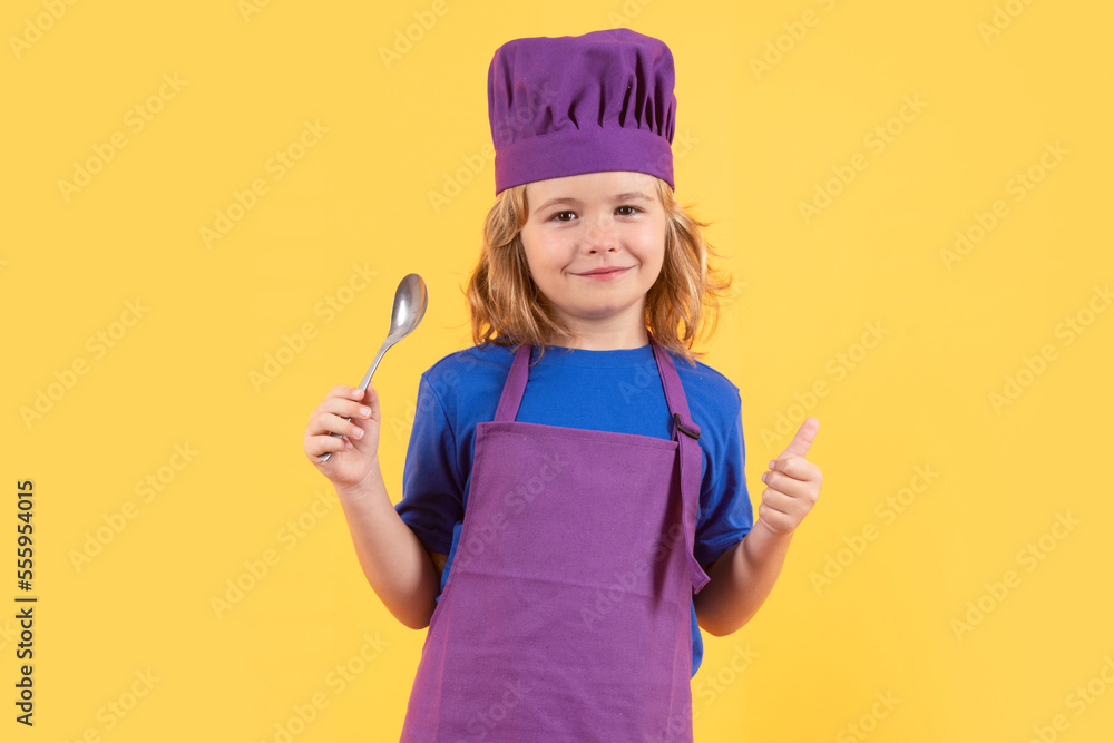 Funny kid chef cook with spoon, studio portrait. Kid in cooker uniform and chef hat preparing food on studio color background. Cooking, culinary and kids food concept. Funny kid chef cook with spoon, studio portrait. Kid in cooker uniform and chef hat preparing food on studio color background. Cooking, culinary and kids food concept.