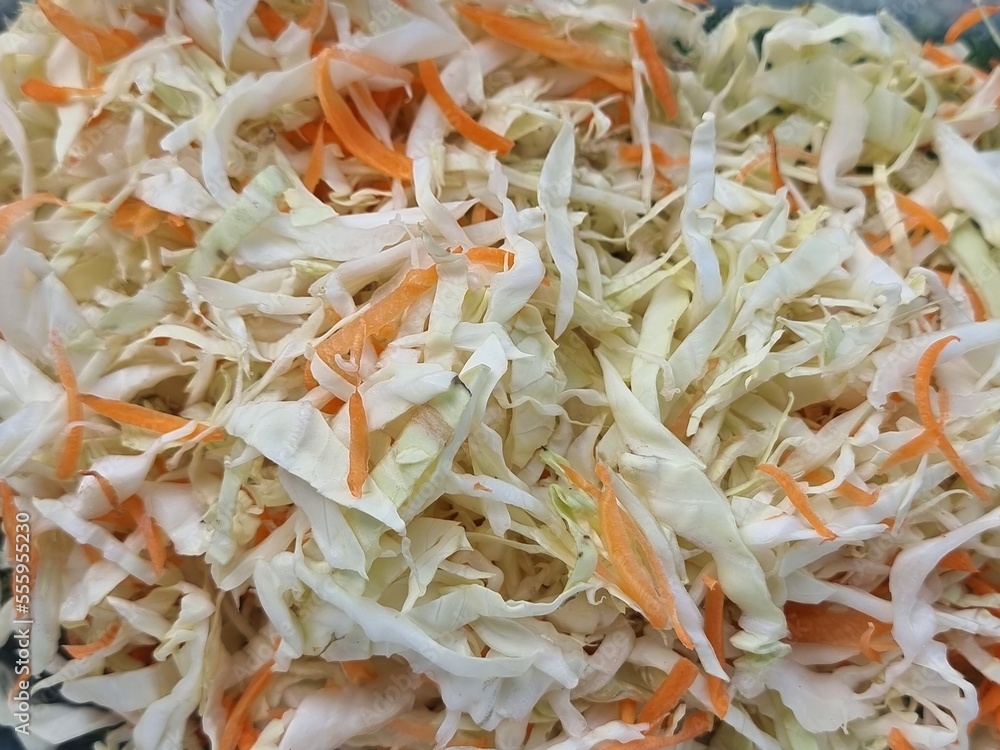 Cabbage and carrots are shredded into small pieces to prepare for a salad. Cabbage and carrots are shredded into small pieces to prepare for a salad.