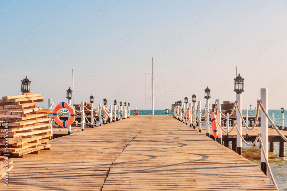 Obraz premium Wooden sea pier in sun lights at the sandy beach