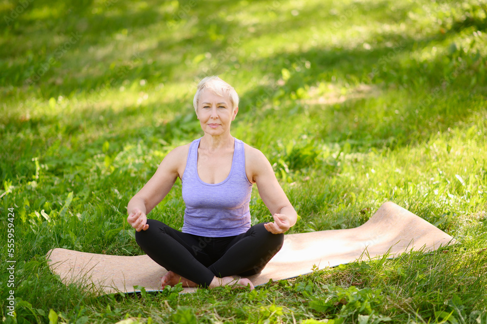 Athletic middle-aged woman doing yoga outdoors in a city park.Meditation concept Athletic middle-aged woman doing yoga outdoors in a city park.Meditation concept