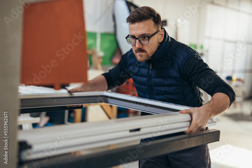 Middle age man works in a workshop and produces PVC window frames
