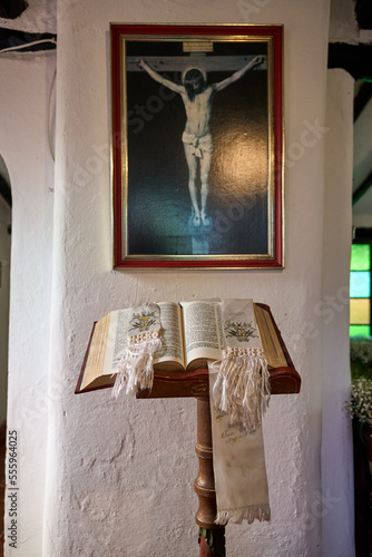 holy bible on a pedestal next to a wall with a picture of Jesus Christ crucified. biblical image. interior of the church. holy mass and reading of the good book. 