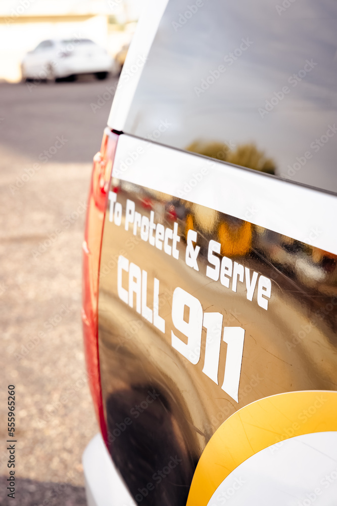 Obraz premium Vertical image of back end of a police car vehicle reading Protect and serve call 911