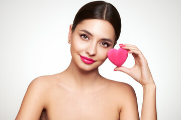 Young beautiful woman with heart-shaped gift. Girl with pure perfect face skin. Cosmetology, beauty and spa. Red nails manicure. Valentine’s Day