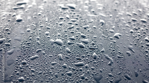 Dew drops on the black hood of a parked car. Background