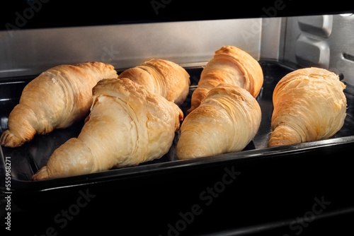 Six baked croissants on tray in electric oven. French cuisine, homemade bakery, breakfast, food, cooking and pastry concept