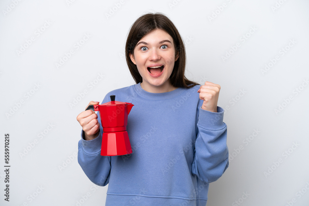 Young Russian woman holding coffee pot isolated on white background celebrating a victory in winner position Young Russian woman holding coffee pot isolated on white background celebrating a victory in winner position