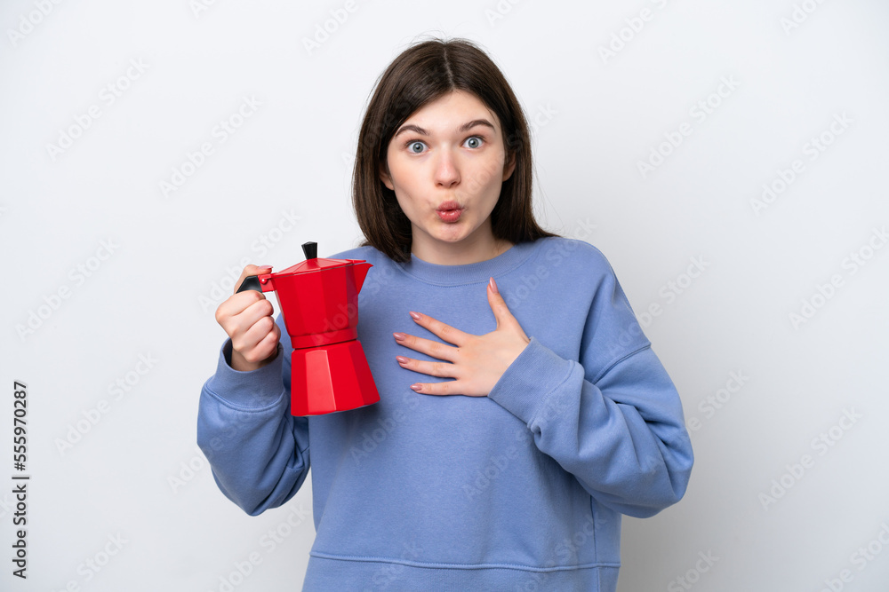 Young Russian woman holding coffee pot isolated on white background surprised and shocked while looking right Young Russian woman holding coffee pot isolated on white background surprised and shocked while looking right