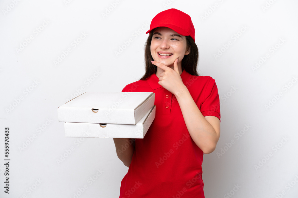 Young Russian pizza delivery picking up pizza boxes isolated on white background looking to the side and smiling Young Russian pizza delivery picking up pizza boxes isolated on white background looking to the side and smiling