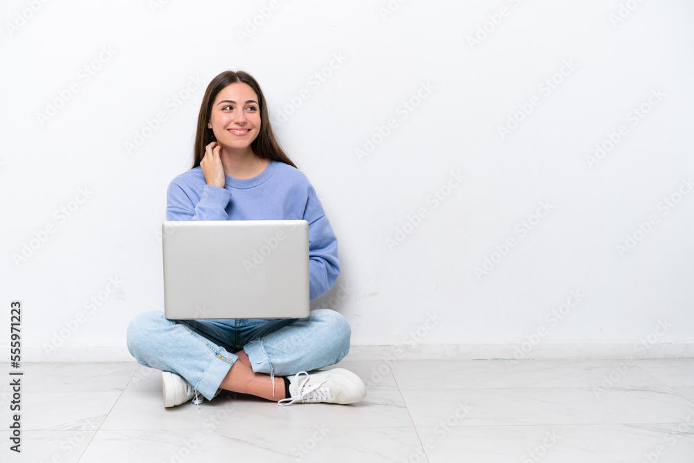 Naklejka premium Young caucasian woman with laptop sitting on the floor isolated on white background thinking an idea