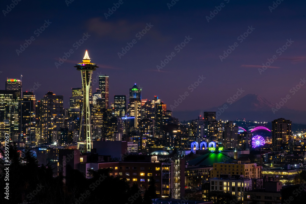 The holiday lights in the Seattle skyline after dark. Mount Rainier is in the background.