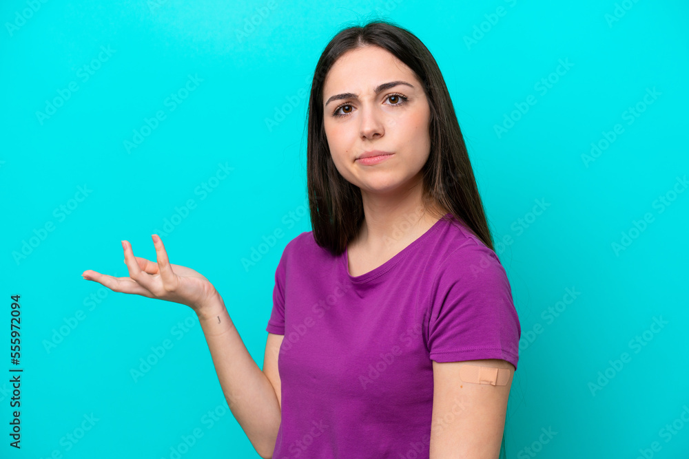 Young girl with band-aids isolated on blue background making doubts gesture while lifting the shoulders Young girl with band-aids isolated on blue background making doubts gesture while lifting the shoulders