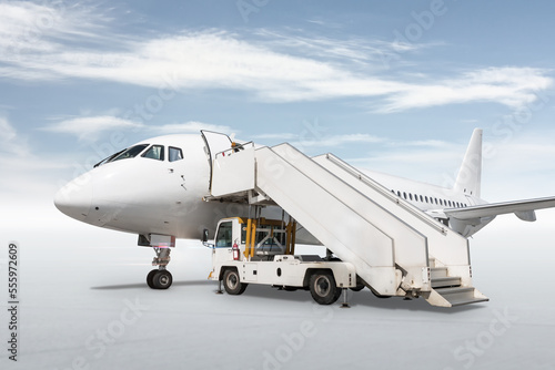 White passenger airliner with a boarding stairs isolated on bright background with sky