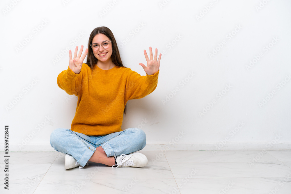 Young girl sitting on the floor isolated on white background counting nine with fingers Young girl sitting on the floor isolated on white background counting nine with fingers