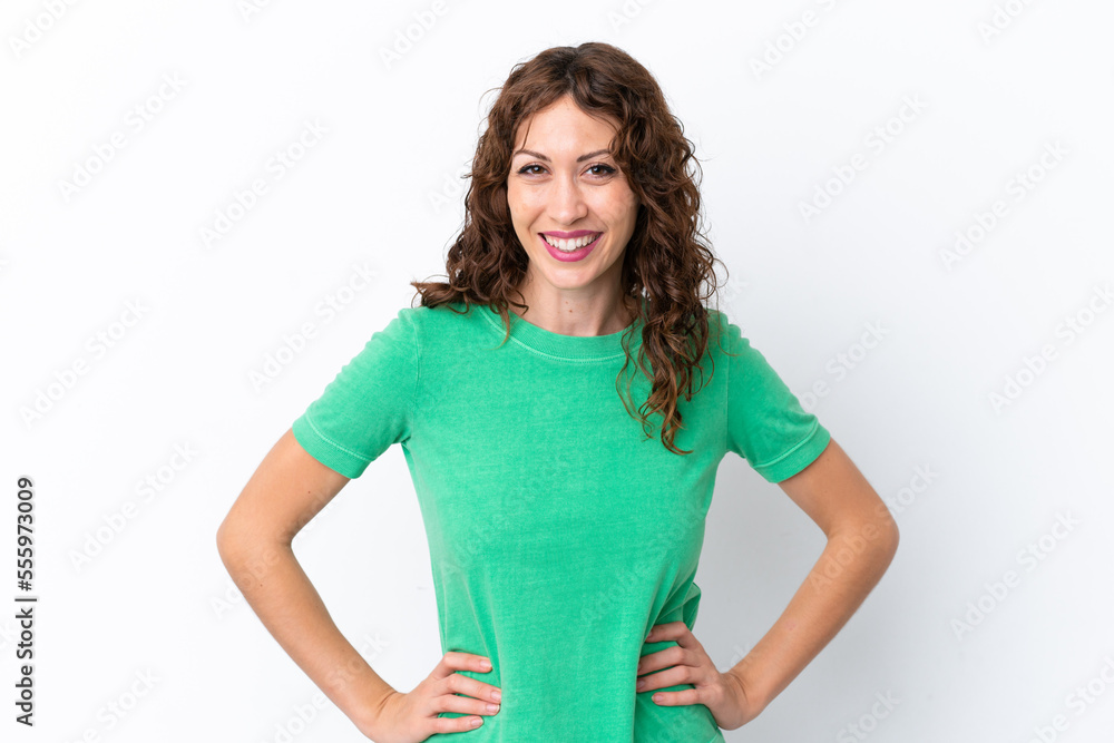 Young woman with curly hair isolated on white background posing with arms at hip and smiling Young woman with curly hair isolated on white background posing with arms at hip and smiling
