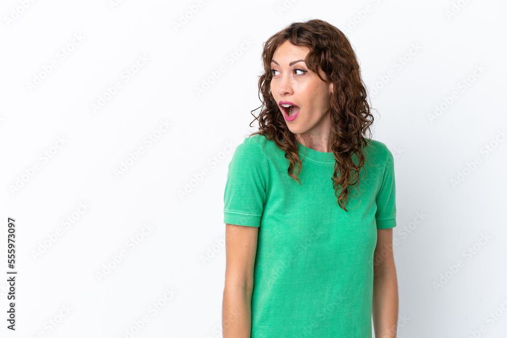 Young woman with curly hair isolated on white background doing surprise gesture while looking to the side Young woman with curly hair isolated on white background doing surprise gesture while looking to the side