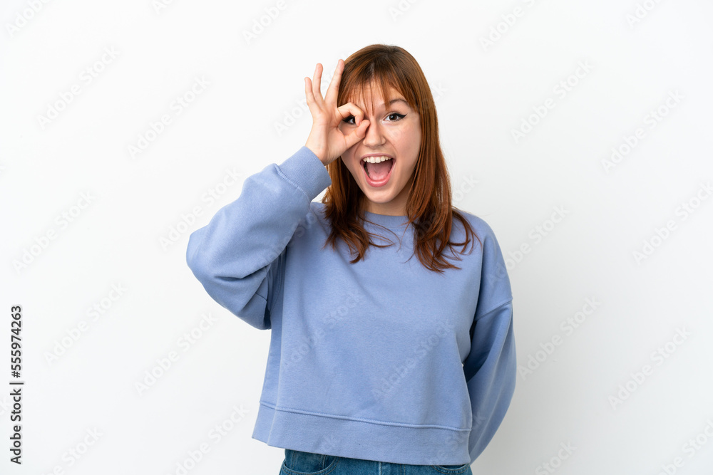 Redhead girl isolated on white background showing ok sign with fingers Redhead girl isolated on white background showing ok sign with fingers