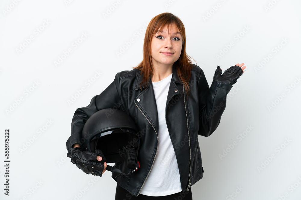 Redhead girl with a motorcycle helmet isolated on white background having doubts while raising hands Redhead girl with a motorcycle helmet isolated on white background having doubts while raising hands