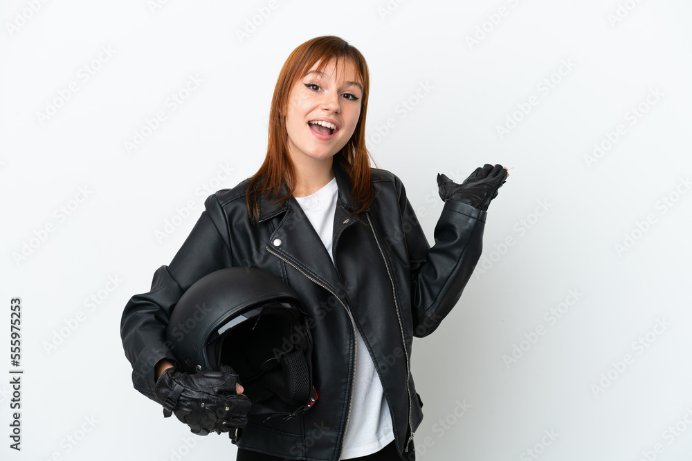 Redhead girl with a motorcycle helmet isolated on white background extending hands to the side for inviting to come Redhead girl with a motorcycle helmet isolated on white background extending hands to the side for inviting to come