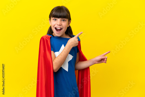 Little super hero kid isolated on purple background surprised and pointing side