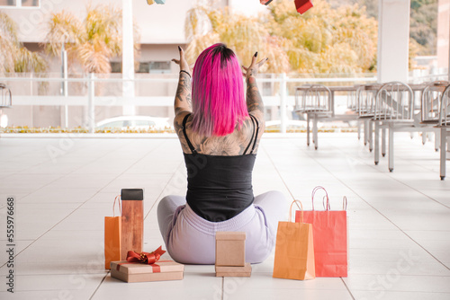 Mulher tatuada jogando caixas e sacolas para presente para cima photo