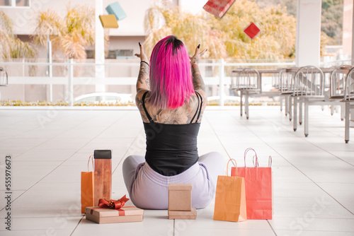 Mulher tatuada jogando caixas e sacolas para presente para cima photo