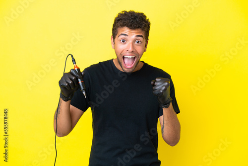 Tattoo artist Brazilian man isolated on yellow background celebrating a victory in winner position