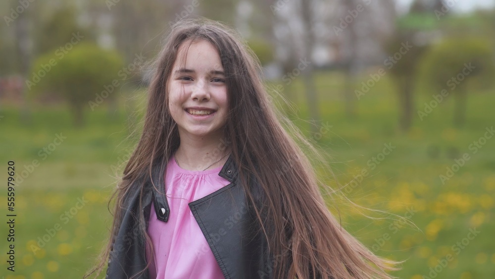 Fototapeta premium A teenage girl with long hair twirls and poses for the camera.